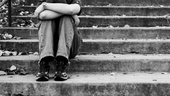 black and white image with someone clutching their knees on steps