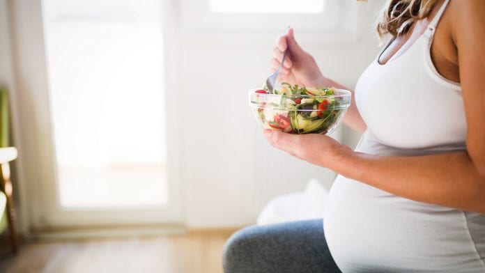 Beautiful pregnant woman eating healthy food and salads