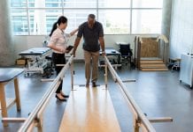 Caring female physical therapist helps stroke victim in rehab centre
