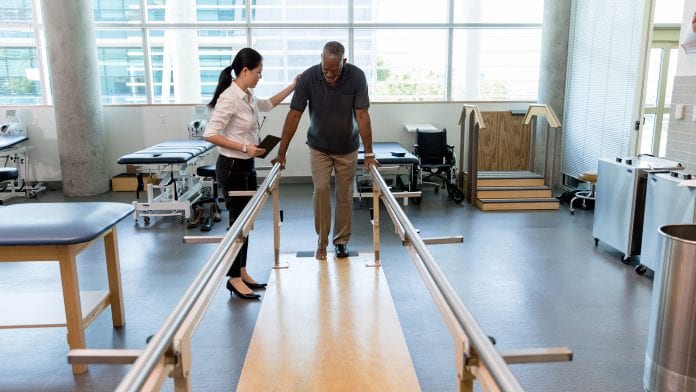 Caring female physical therapist helps stroke victim in rehab centre