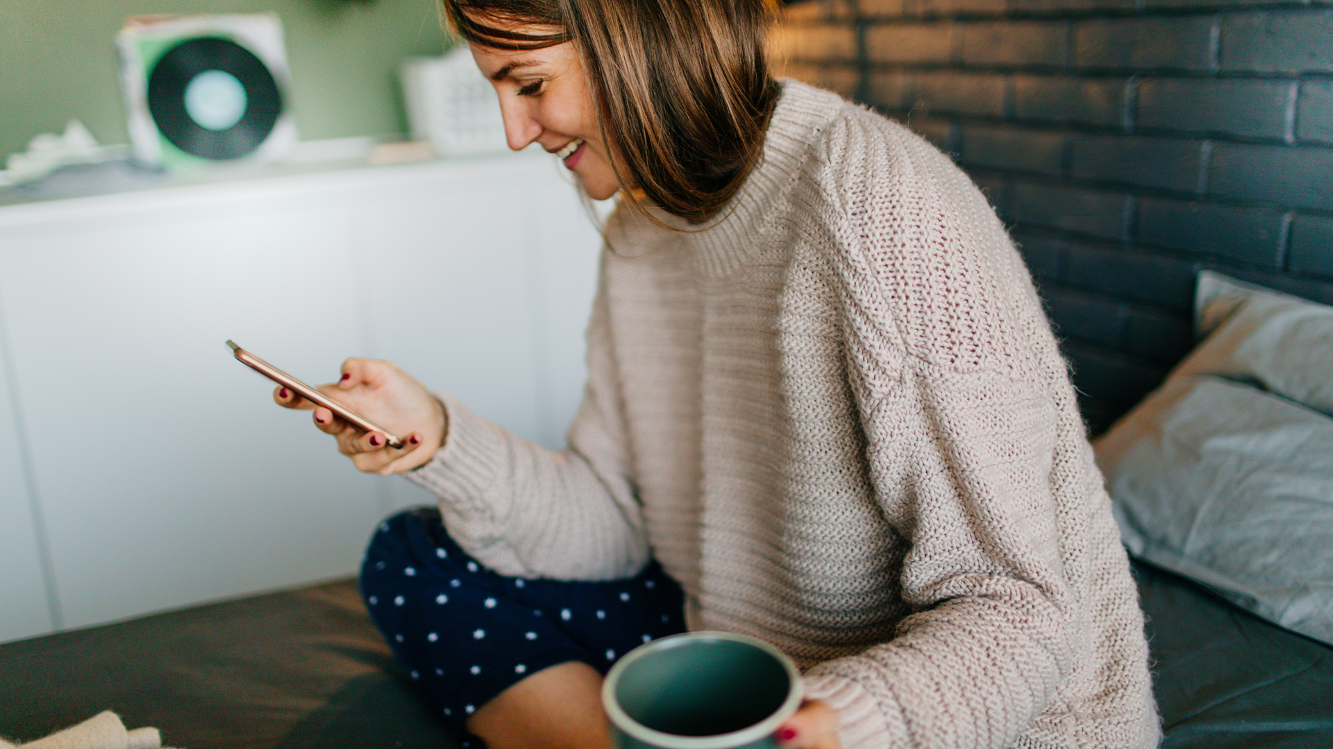 woman looking at mobile phone with drink