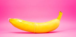 Transparent condom placed on banana. concept of sexual protection