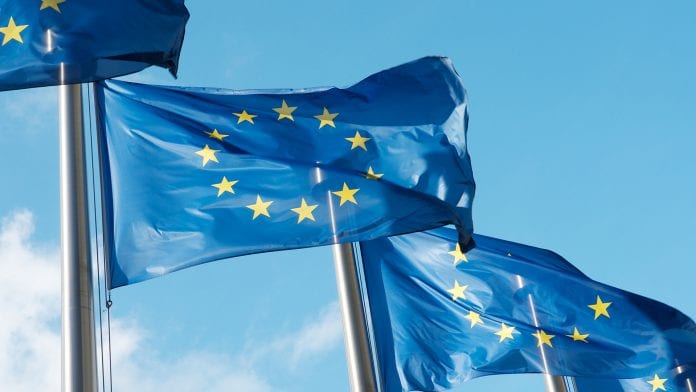 Row of blue European Union flags in Brussels. The blue flags have twelve yellow stars depicting the original number of member states