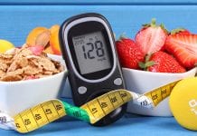 Glucometer with result of measurement sugar level, healthy food, dumbbells for fitness and tape measure, concept of diabetes, slimming, healthy lifestyle