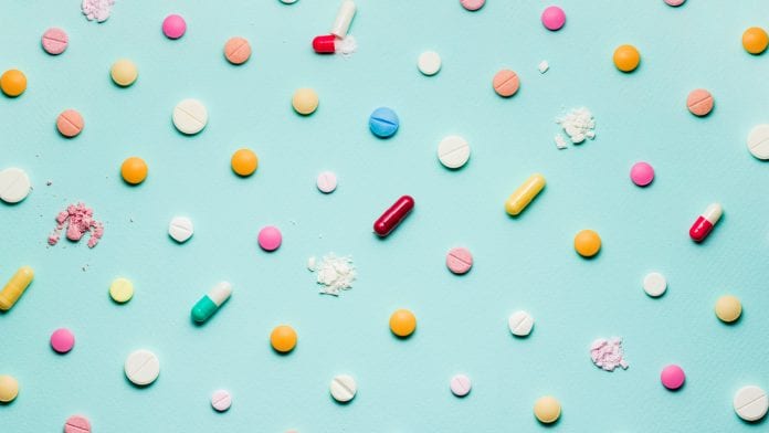 A photo of different medicinal drugs, tablets and pills on blue background