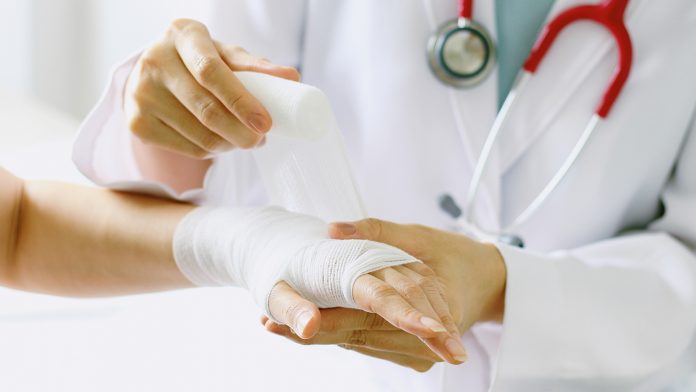 Close-up of female doctor with stethoscope bandaging hand of patient. wound healing