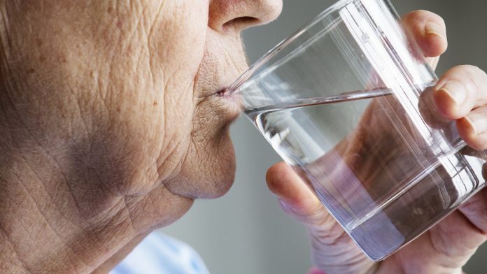 Side view of elderly woman drinking water dehydration in older adults