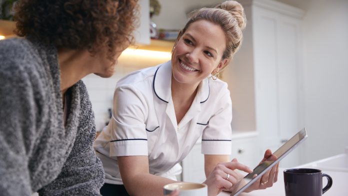 Mature Woman In Dressing Gown At Home Talking With Female Nurse With Digital Tablet women's health