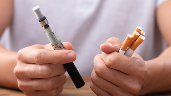 Man Holding Vape And Cigarette smoking cessation