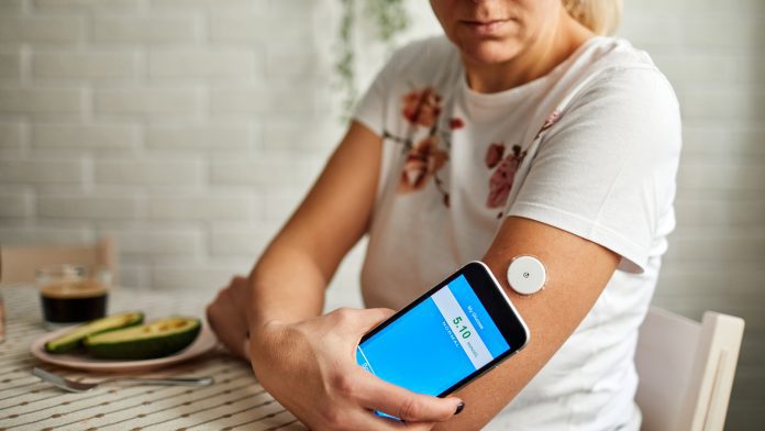 Mature Woman Swiping Sensor With Smart Phone For Glucose Mesaurement flash glucose monitors