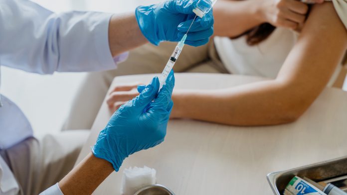 Female patient getting a vaccine injection from a doctor Valneva COVID-19 vaccine approved by MHRA