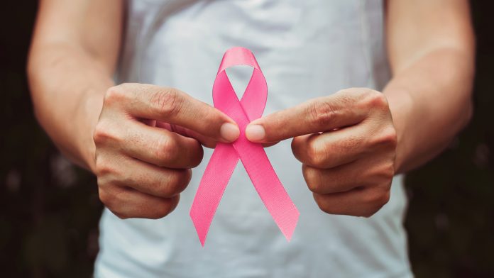 concept healthcare and medicine. hand holding pink ribbon. breast cancer awareness. sign of hope breast cancer in men