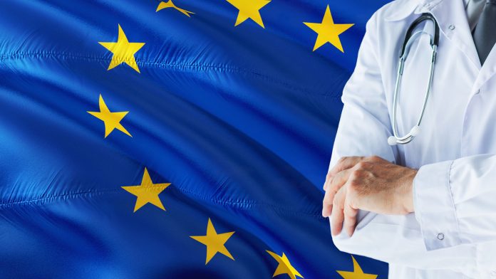 European Doctor standing with stethoscope on European Union flag background. National healthcare system concept, medical theme.European Doctor standing with stethoscope on European Union flag background. National healthcare system concept, medical theme.E EIT Health