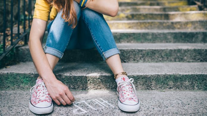 Unahppy girl writes help on the ground young people’s mental health