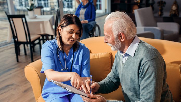 Female nurse talking to senior man at nursing home. healthcare staff