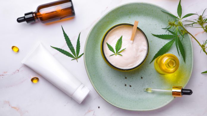Cosmetics with cannabis oil on a turquoise plate on a light marble background. Copy space, mockup. topical CBD