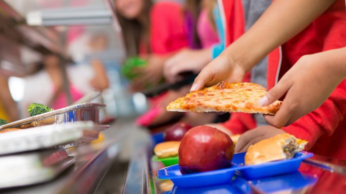School children getting food in the cafeteria line ultra-processed food
